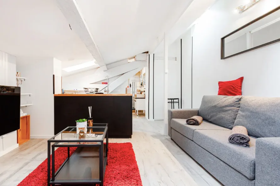Studio sous les toits, canapé gris et tapis rouge